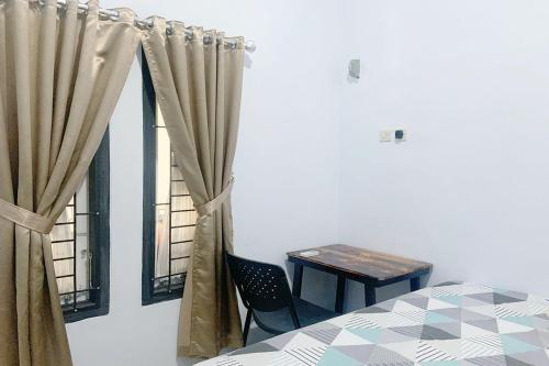 明古鲁省Pondokan Guest House Rinjani Syariah的一间卧室配有桌子和窗帘的窗户