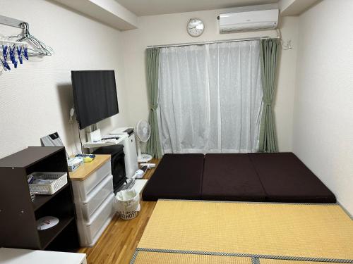 鹿儿岛短期賃貸ビッグバーンズマンション田上的一间卧室配有一张床、一台电视和一张书桌