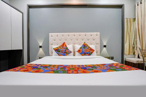 纳威孟买FabHotel Grand Inn I的卧室配有白色的床和色彩缤纷的毯子
