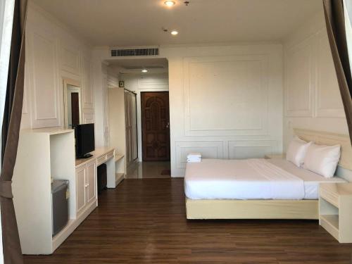 信武里府金龙度假酒店的卧室配有白色的床和电视。