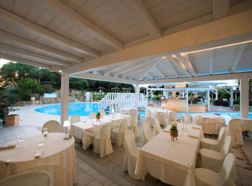 默塔玛丽亚Hotel Sa Pedra的一间带白色桌椅的餐厅和一个游泳池