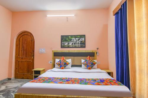 库尔卢FabExpress Malti Guest House的一间卧室配有橙色墙壁和蓝色窗帘的床