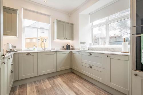 金斯巴恩斯Daisybank Kingsbarns - Beautiful 3 Bedroom Cottage的厨房配有白色橱柜和2扇窗户。
