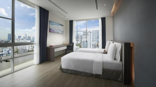 曼谷曼谷莎玛素坤逸服务式公寓的卧室设有一张白色大床和大窗户