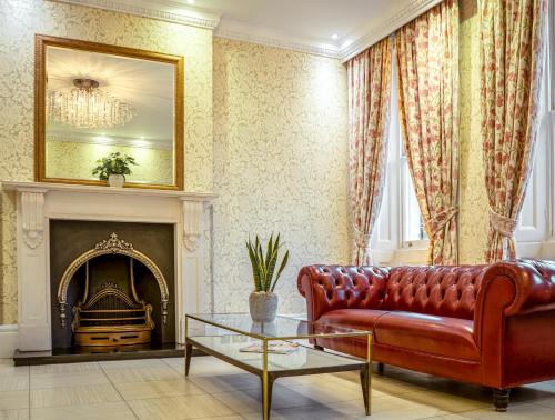 伦敦Athena Hotel的客厅设有红色的沙发和壁炉
