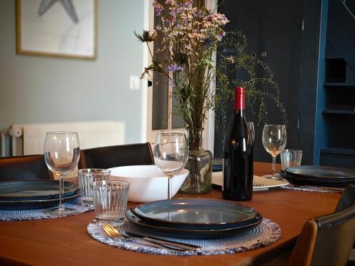 莫尔莱Les Hauts de Morlaix的一张木桌,配有一瓶葡萄酒和玻璃杯