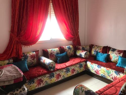 丹吉尔Appartement Tanger diari的客厅配有带蓝色枕头的红色沙发