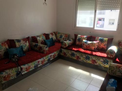 丹吉尔Appartement Tanger diari的客厅配有红色沙发及色彩缤纷的枕头