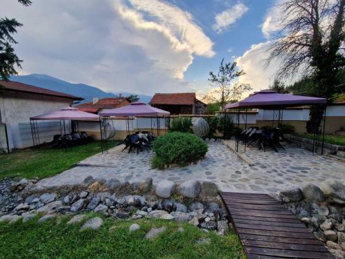 多布里尼什特Семеен хотел Света Марина的一个带紫色雨伞和桌椅的庭院