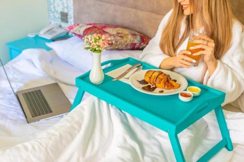 巴库Sahil Inn Baku Hotel Formula 1 View的坐在床上的女人,桌子上放着一盘食物