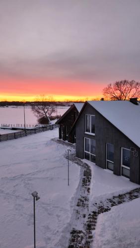 雷泽克内Add Story Guest House的雪中的房子,背景是日落