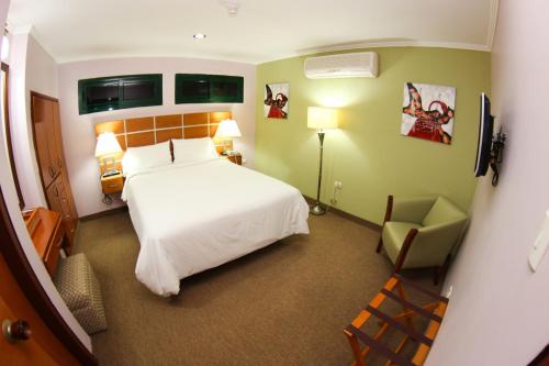 Punto FijoSanta Fe Inn Hotel的卧室配有白色的床和椅子