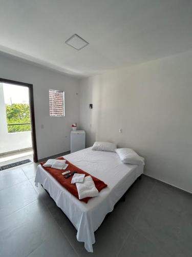 弗洛里亚诺波利斯Pousada Tamatoa Suítes的白色卧室配有一张大床和毛巾