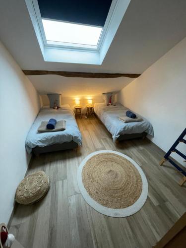 力宾Le grenier de Charlotte的一间设有两张床的客房,地板上铺有地毯。