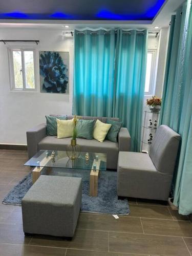 La CaletaJC Caribe Aparta Hotel #1的客厅配有蓝色窗帘和沙发