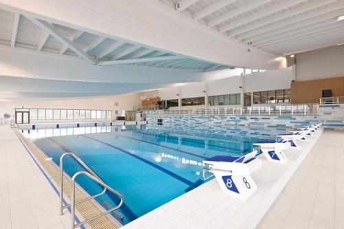 Saint-GhislainComfortable house G00gle-SHAPE- Chièvres Air Base的大房间设有一个大型游泳池,配有椅子