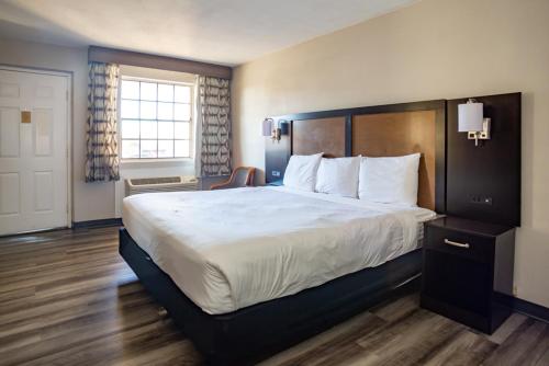 奥斯汀Baymont by Wyndham Austin University Area的酒店客房带一张大床,带白色床单
