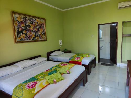库塔Berlian Inn Kuta Beach的绿墙客房内的两张床