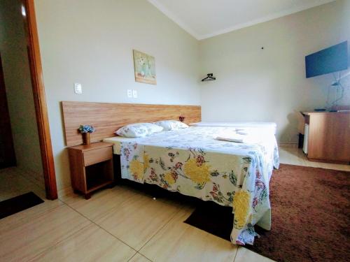 圣若昂-巴蒂斯塔-杜格罗里亚Pouso Oliveira Suítes的一间卧室配有一张带木制床头板的床
