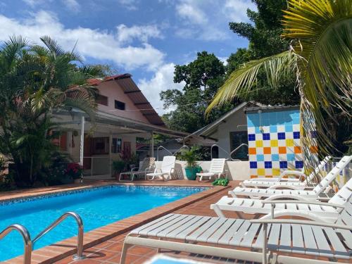 圣达菲Rainforest Yasmin Hotel的一座房子旁的游泳池,配有白色躺椅
