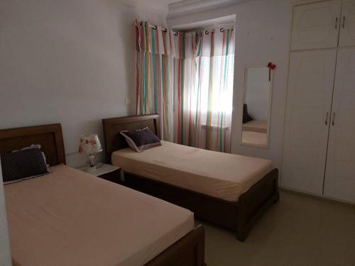 甘达坞伊港Résidence Sayadi - Chatt Meriam - Sousse的一间卧室设有两张床,窗户配有窗帘