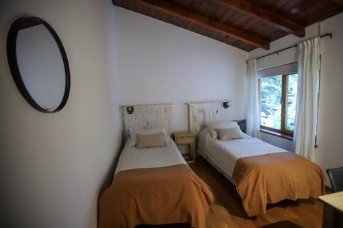 圣卡洛斯-德巴里洛切Hostería Carelhue的一间卧室配有两张床和镜子