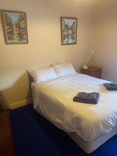 坎伯当Commercial Hotel Camperdown的卧室配有一张白色床,墙上挂有两张照片