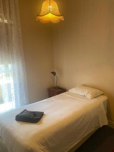 坎伯当Commercial Hotel Camperdown的卧室配有白色床、灯和窗户