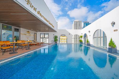 岘港Golden Lotus Hotel Da Nang的大楼内带桌椅的游泳池