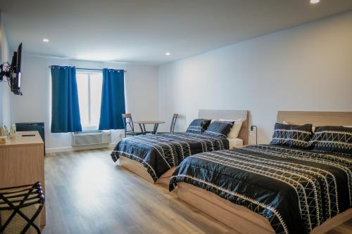 Saint-RaymondHôtel St-Alexis的卧室内的两张床,配有蓝色窗帘