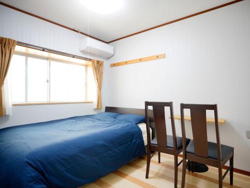 那霸Mcity in Maejima - Vacation STAY 54941v的一间卧室配有蓝色的床和两把椅子