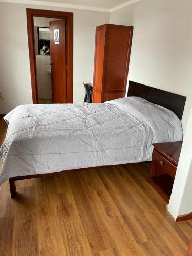 卡哈马卡Hotel Hispano的一间卧室配有一张床,铺有木地板