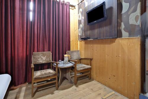 贾姆穆OYO Hotel Azad的一间设有两把椅子、一张桌子和一台电视的房间