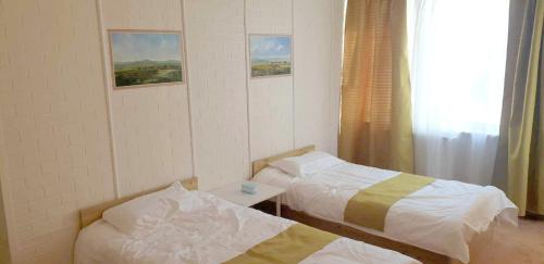 乌兰巴托Gandan Terrace Guesthouse的客房设有两张床、一张桌子和一扇窗户。