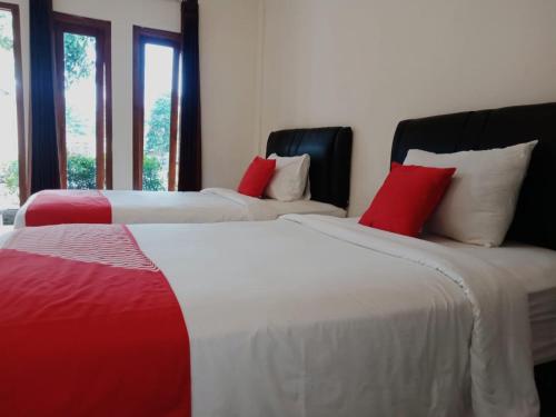 谏义里Rahayu Residence Syariah Kediri的红色和白色的客房内的两张床