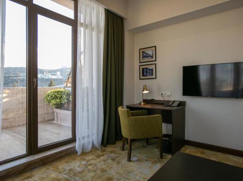 第比利斯柑橘酒店的酒店客房设有一张书桌和一个大窗户。