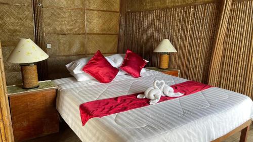 Phumĭ Kaôh ÂndêtTatai Natural Resort的两个塞满食物的动物坐在床上,床上放着红色枕头