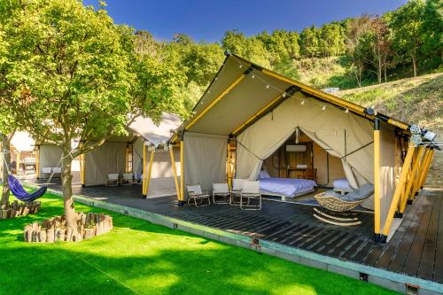 苗栗市山上種樹 l 苗栗豪華懶人露營Glamping l 柴燒泡湯 l 可包區森林系狩獵帳 l 牛樟森林休閒農場的甲板上配有吊床的豪华帐篷