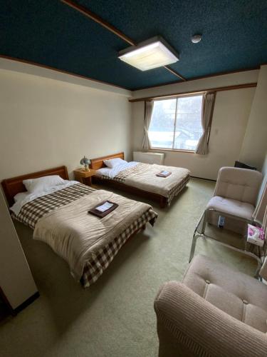 藏王温泉ロッヂ　スガノ的客房设有两张床、椅子和沙发。