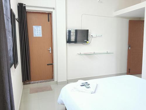蓬蒂切里Rose Villa Pondicherry的一间设有床、门和电视的房间