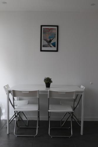 索塞莱潘La Locomotive- SPA - 400 m de la plage的一张白色的桌子和椅子,墙上挂着一张照片