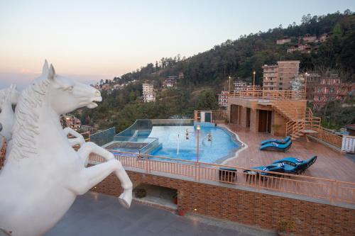 图利凯尔Hotel Sarathi的一座带游泳池的建筑顶部的白马雕像