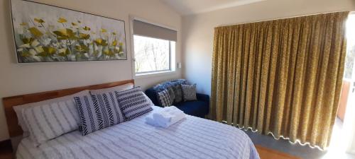 AlonnahKaoru on Bruny的一间卧室配有一张床、一张沙发和一个窗口