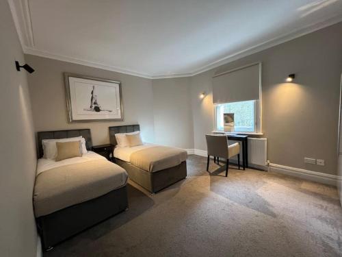 伦敦Star London Warwick Mansions 3-Bed Oasis的一间卧室设有两张床、一张桌子和一个窗口。