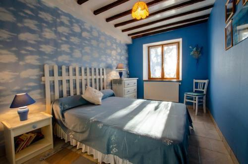 RacinesLes colchiques的一间拥有蓝色墙壁的卧室、一张床和窗户