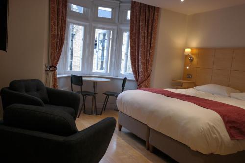 伦敦The Alma Rooms的配有床、椅子和桌子的酒店客房