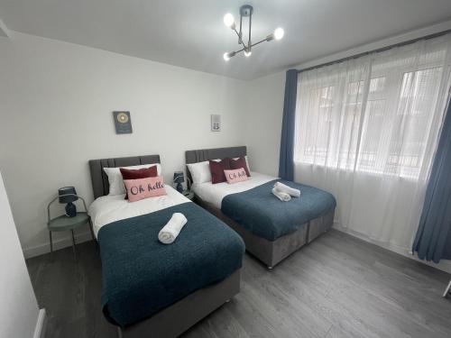 伦敦Deluxe Apartment - Next to Kings Cross - Eurostar & Euston Station的一间卧室设有两张床和窗户。