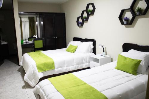 埃雷迪亚Hotel América Heredia的配有两张床铺的酒店客房,配有绿色和白色床单