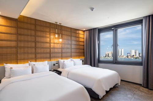 束草市Sokcho Business Hotel CAMEL的配有窗户的酒店客房内的两张床