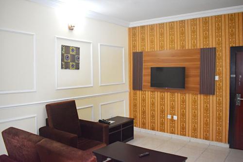 哈科特港DAVIS HOTEL AND SUITES的客厅配有沙发和墙上的电视